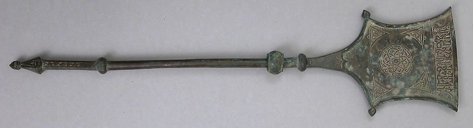 12th Century. Iran. This object made of leaded brass (lead, zinc and copper) is hammered, cast and incised. It has a pentagonal blade with upturned sides. Two angles of the blade terminate in floral form with a slightly flaring edge. In center of the blade is a complex pattern with a circular medallion, interlaced hexagons, band with cable pattern, circles, interstitial triangles and hook-like projections. On the edge is a band with floriated kufi inscription terminating in a semicircle at each side. Where top of blade is joined to handle, an arabesque scroll contains in foliated kufi the words lillah, i.e. for God. Inscription in Kufic: Happiness and blessing and ... H. 22 7/8 in. (58.1 cm) W. 5 1/2 in. (14 cm) D. 1 1/8 in. (2.9 cm) Wt. 1.8lb. (0.8kg). Accession no. 1975.266.