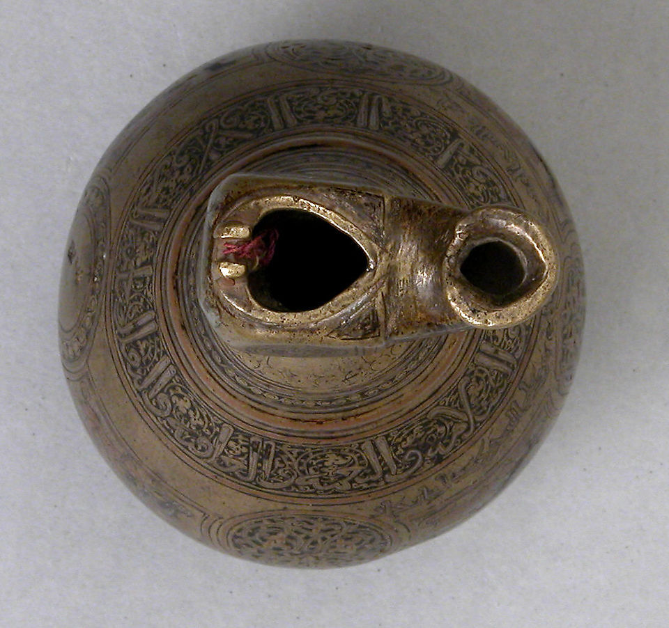 12th Century. Iran. Brass; cast, engraved, inlaid with silver, copper and black compound. Inscriptions in Arabic: Glory and prosperity and power and happiness and security and favor and good health and long life to the owner. Its owner [is] the Shaikh, the theologian, Ahmad son of `Ali of Sistan. Its owner [is] Ahmad son of Muhammad ... [a later owner, no doubt]. Good fortune, and blessing and power and joy and happiness and security and favor and good health and nobility and victory and ... and long life to the owner. Blessing and power and joy and assistance. H. 6 in. (15.24 cm). Accession no. 54.64.