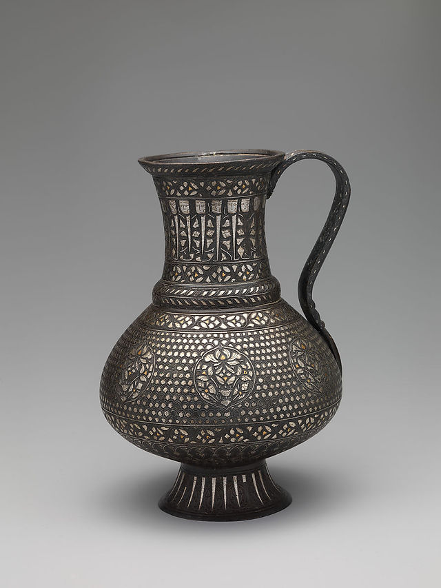 Second half of the 13th Century. Iran. Bronze; cast with handle cast separately, chased, engraved, inlaid with silver and gold. H. 8 9/16 in. (21.7 cm) W. 6 1/2 in. (16.5 cm) D. 6 in. (15.2 cm) Wt. 40.9 oz. (1159.6 g). Illegible inscription. Accession no. 63.158.3.