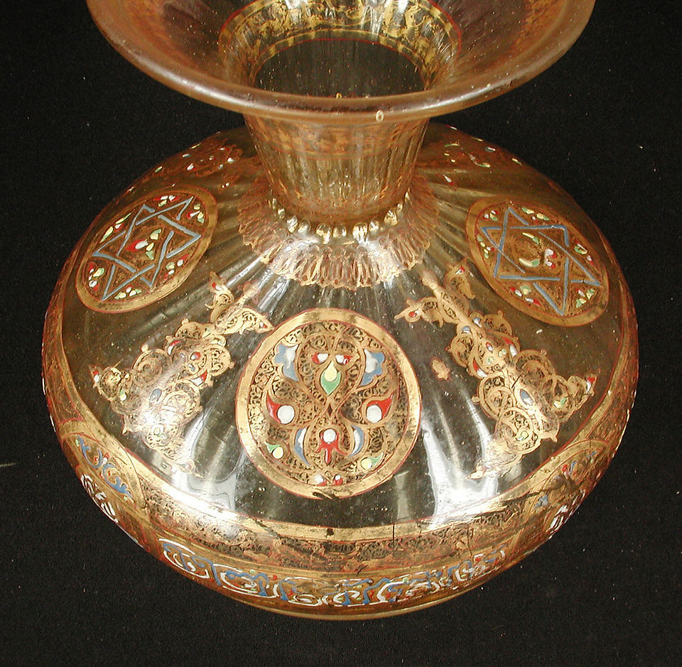 Mid-13th Century. Probably Syria. Glass, colorless with yellow tinge; dip-molded, blown, applied dip-molded blown foot, stained, enameled, gilded. Inscription in naskhi: His (Her) face is like the brilliant shining moon, The posture like a tender blooming sprout. A poem by Jaʻfar ibn Muḥammad Ibn Mukhtār (A.H. 543–622 /A.D. 1148–1225). H. 7 3/16 in. (18.3 cm) Max. Diam. 8 in. (20.3 cm) Diam. of Base: 5 in. (12.7 cm). Accession no. 91.1.1538.