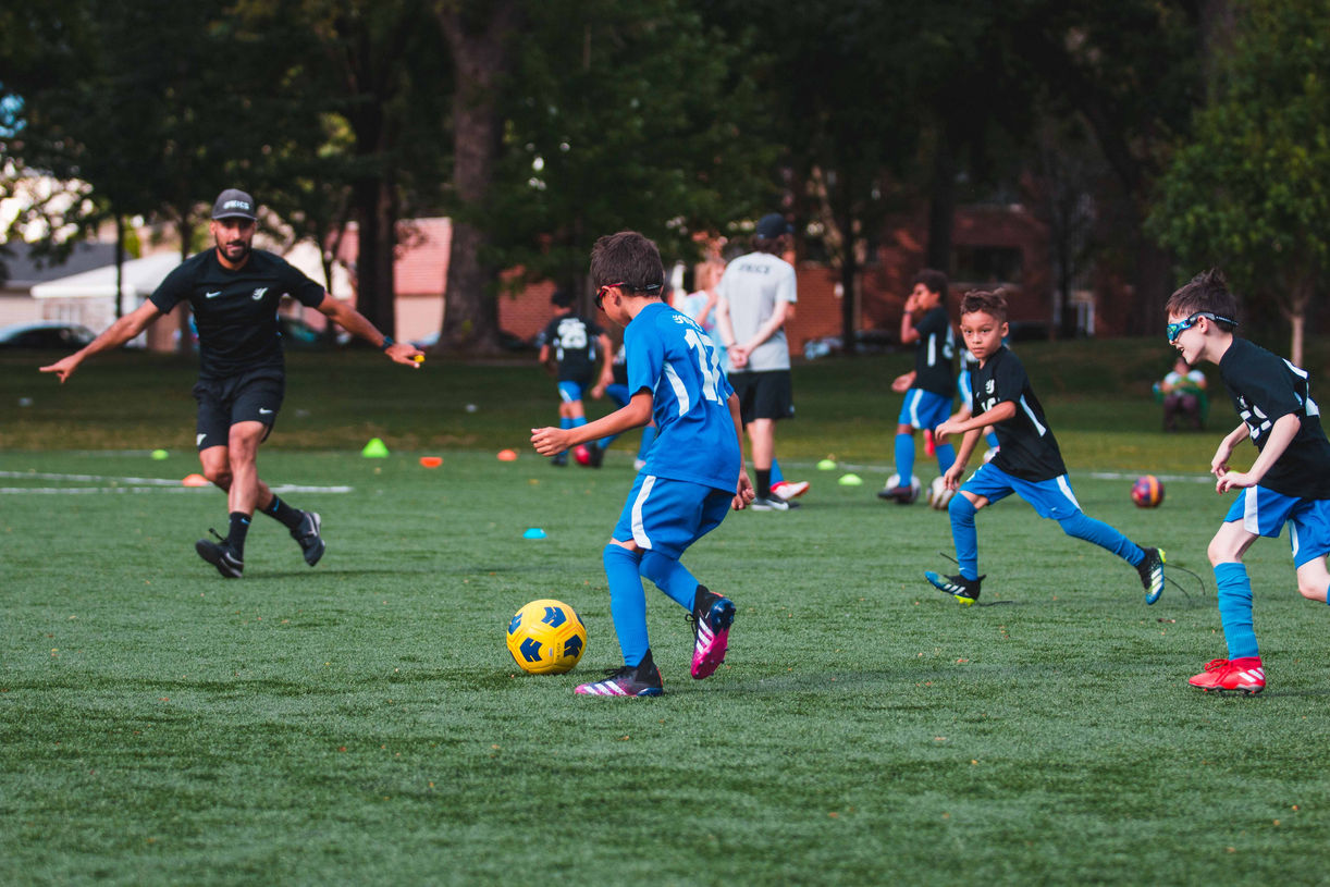 Coach Reinaldo Larotta teaching kids how to play soccer