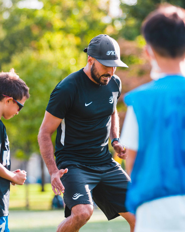 Coach Reinaldo Larotta teaching kids how to play soccer