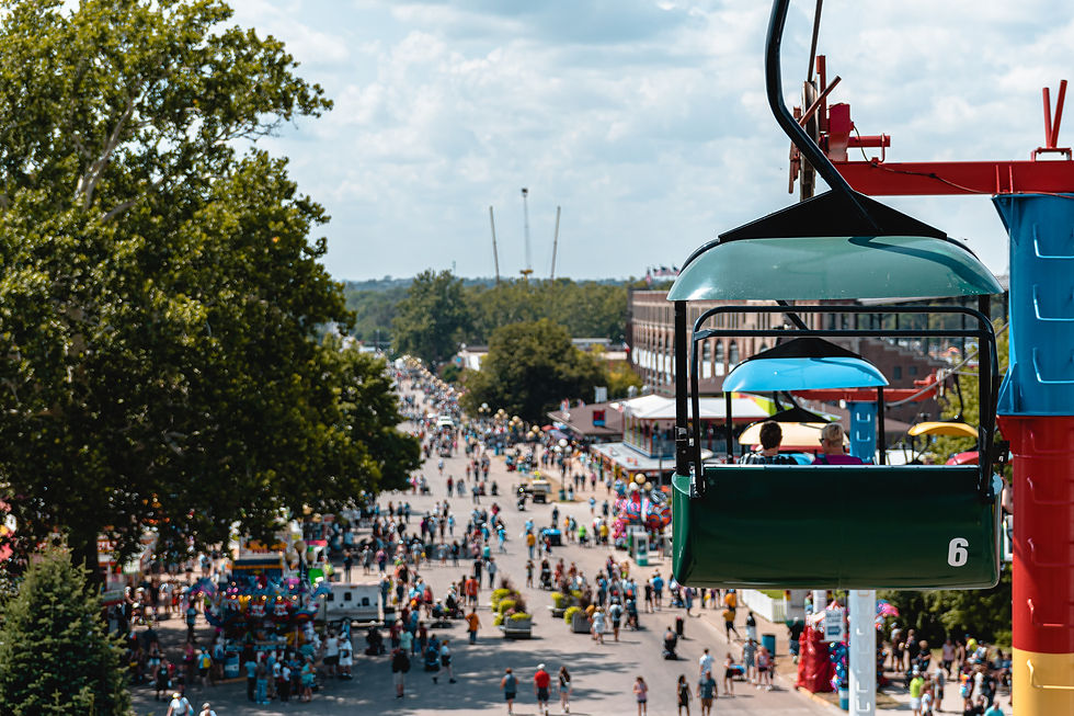 Couple riding the "Sky Glider" at the Iowa State Fair with scattered patrons below and thrill rides in the distance