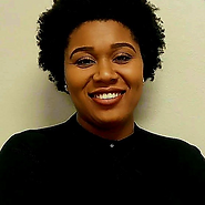 A woman wearing a black polo shirt and earrings, smiling.