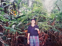 Jungle like leaves and trees, Rebecca looking up with binoculars