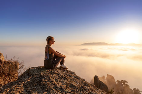 beautiful young athletic girl looking at the sun in the mountains, view from the back, the
