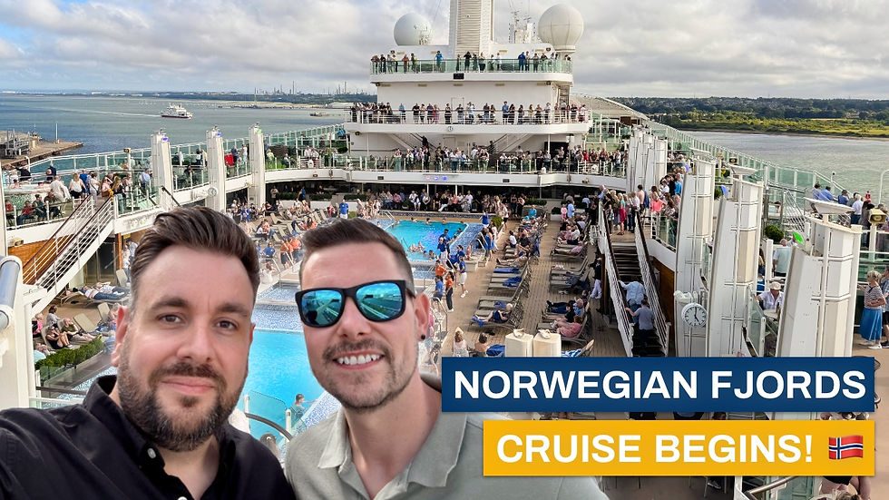 Two men smiling on a crowded cruise ship deck with a pool. Sign reads "Norwegian Fjords Cruise Begins!" with a Norwegian flag.