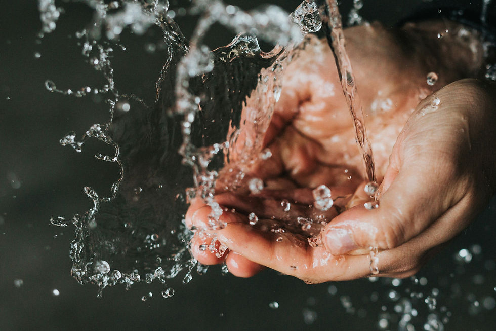 Hands catching splashing water droplets against a dark background, creating a dynamic and refreshing scene.