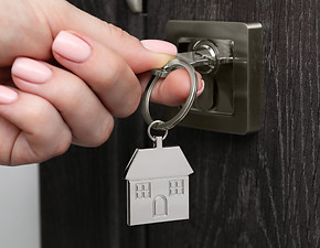 hand using house key in lock