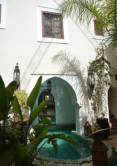 Moroccan riad courtyard with pool and cream and green aesthetic, and palms