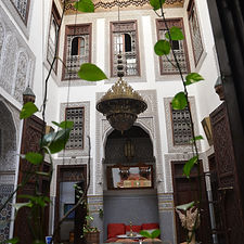 Fez internal courtyard of a riad with large carved wooden doors and intricate tiling