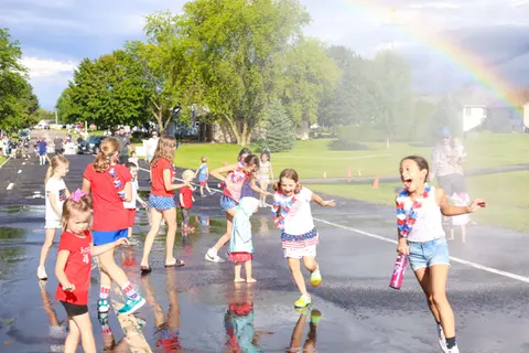 Children playing under the firetruck mister with a rainbow in the spray at WaunaBoom