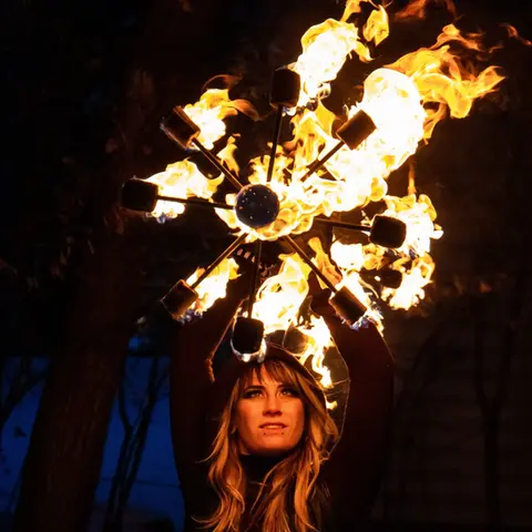 Performer holding flaming fire prop during Cirque du Cham Fire Arts Show at WaunaBoom.