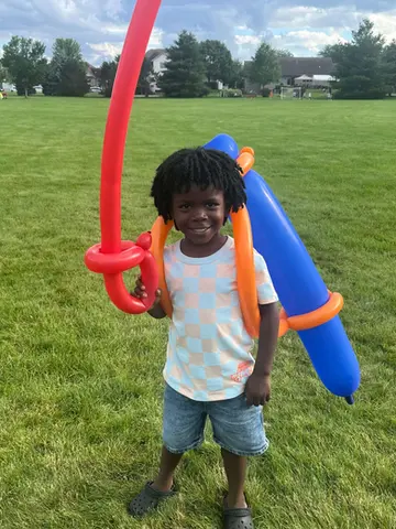 Smiling boy holding a balloon sculpture made by a WaunaBoom balloon artist