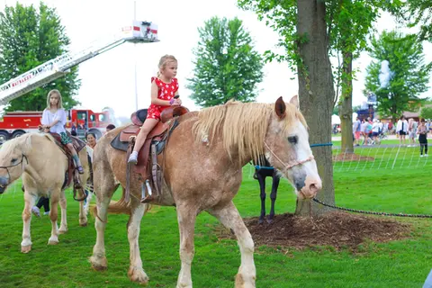 Little girl riding a pony at WaunaBoom with a handler leading on foot