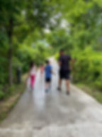 Family walking along a paved path surrounded by lush greenery at Florida Caverns State Park.