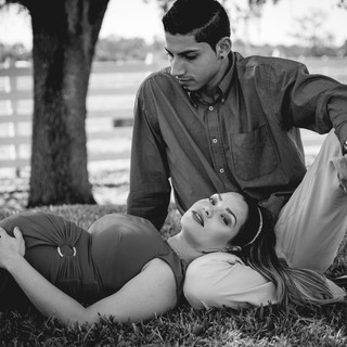 pregnant woman laying down touching her belly with father looking at belly