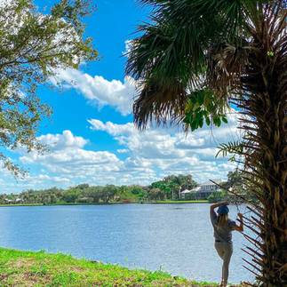 girl standing next to tree in front of river