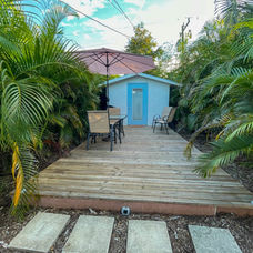 Wooden deck with table, chairs, and pink umbrella with solar lights.