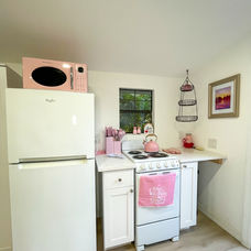 Tiny kitchen in The Pink Casita with refrigerator, stove, and pink microwave.