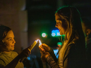 Two kids smiling holding candles.