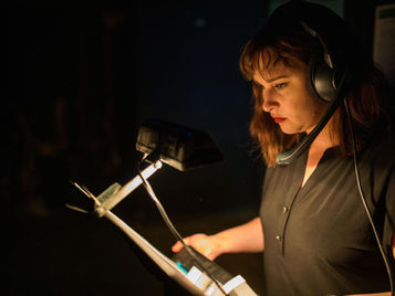 Person backstage with a headset on reading notes.