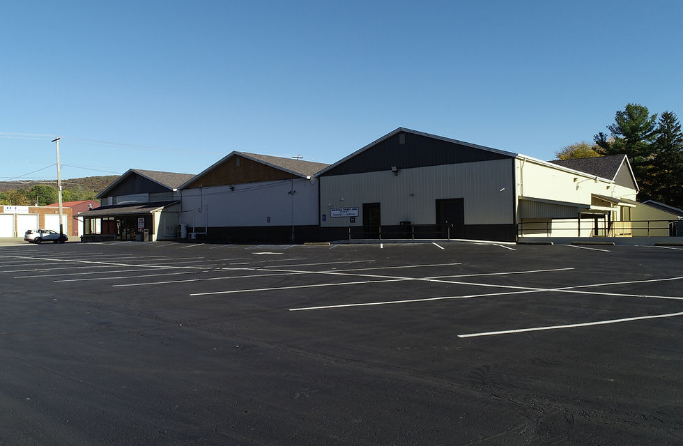 Brown and white plaza building with three arches and a parking lot.