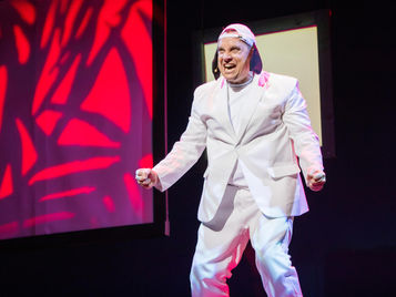 Actor portraying Snoopy standing on stage singing.