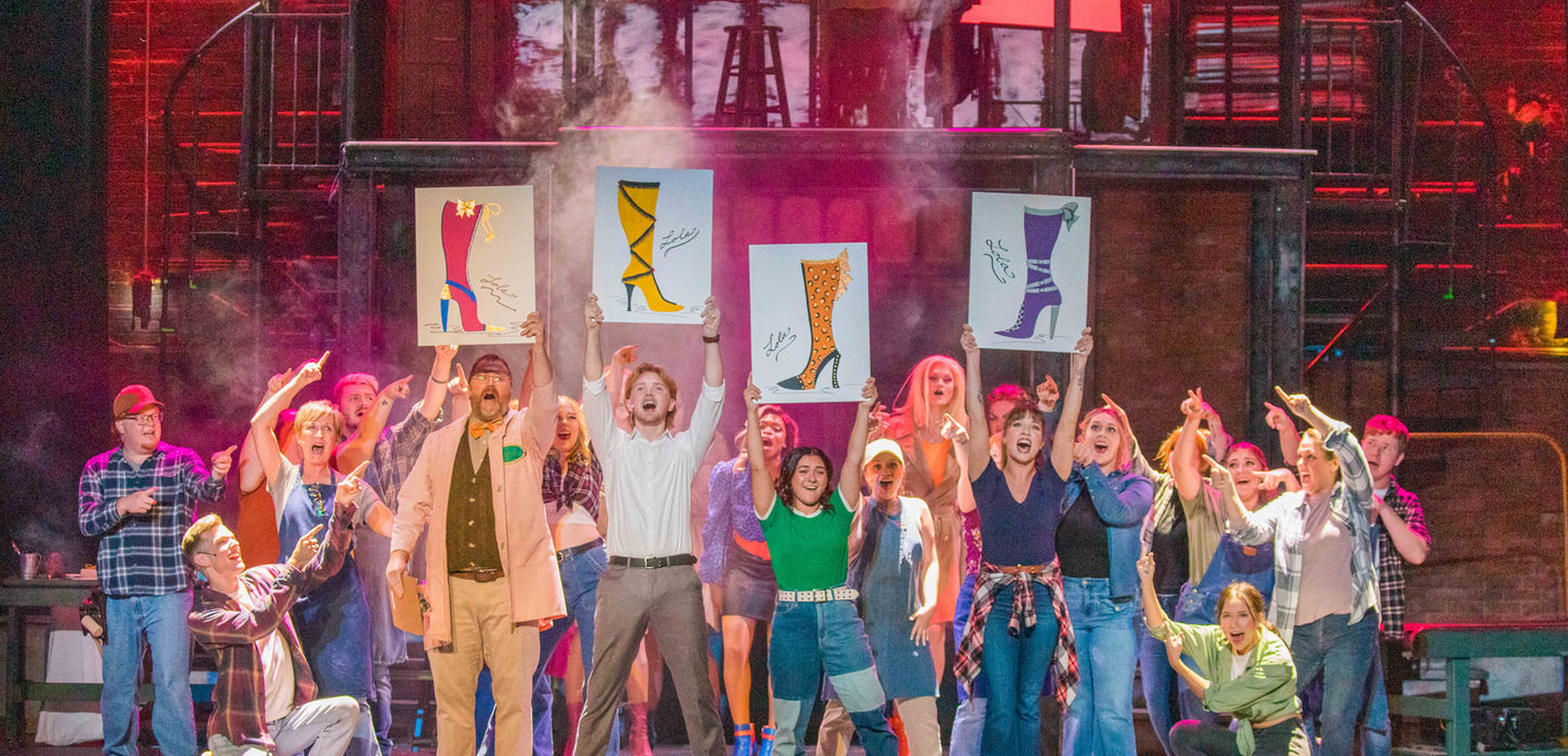 Large group of actors standing on stage performing.