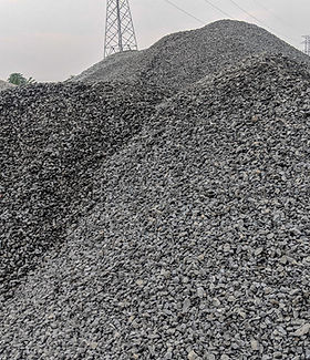 Large piles of crushed stone or gravel at a construction material site, commonly used for