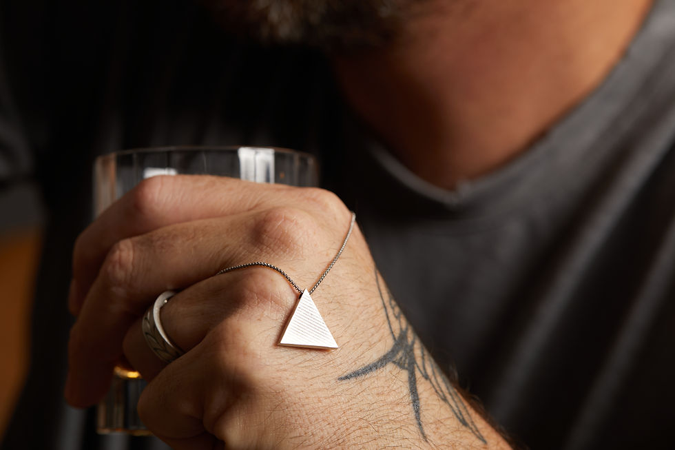 Thumbnail: Close-up of a men’s sterling silver triangle pendant necklace featuring a brushed finish and small pavé diamonds on the top,
