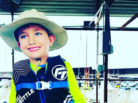 Boy in life jacket smiling on the dock.