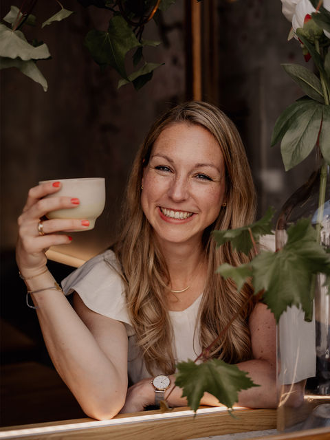 Frau sitzt am Fenster und trinkt Kaffee