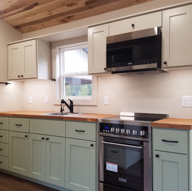 Butcher block counter tops tiny house. Light green painted cabinets.
