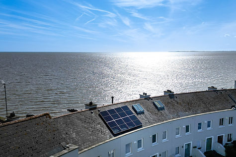 a row of houses by the sea in Blackrock, Dundalk, Ireland with one of the roofs having solar panels on top of it