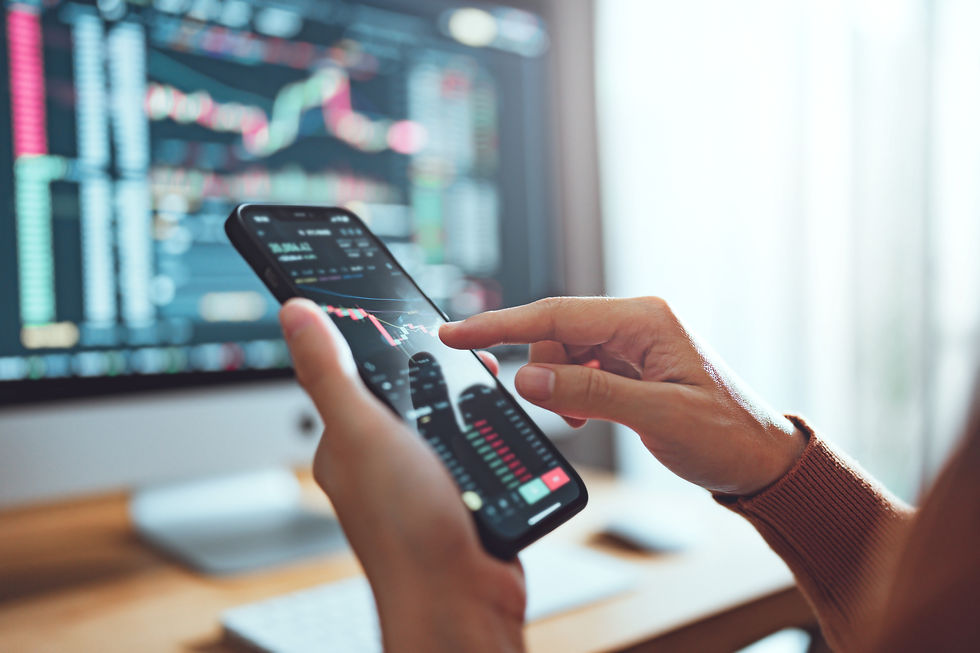 Investing on a phone with computer in the background
