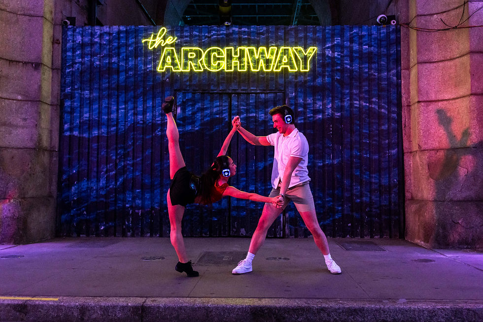 2 dancers in front of the Archway Plaza sign DUMBO