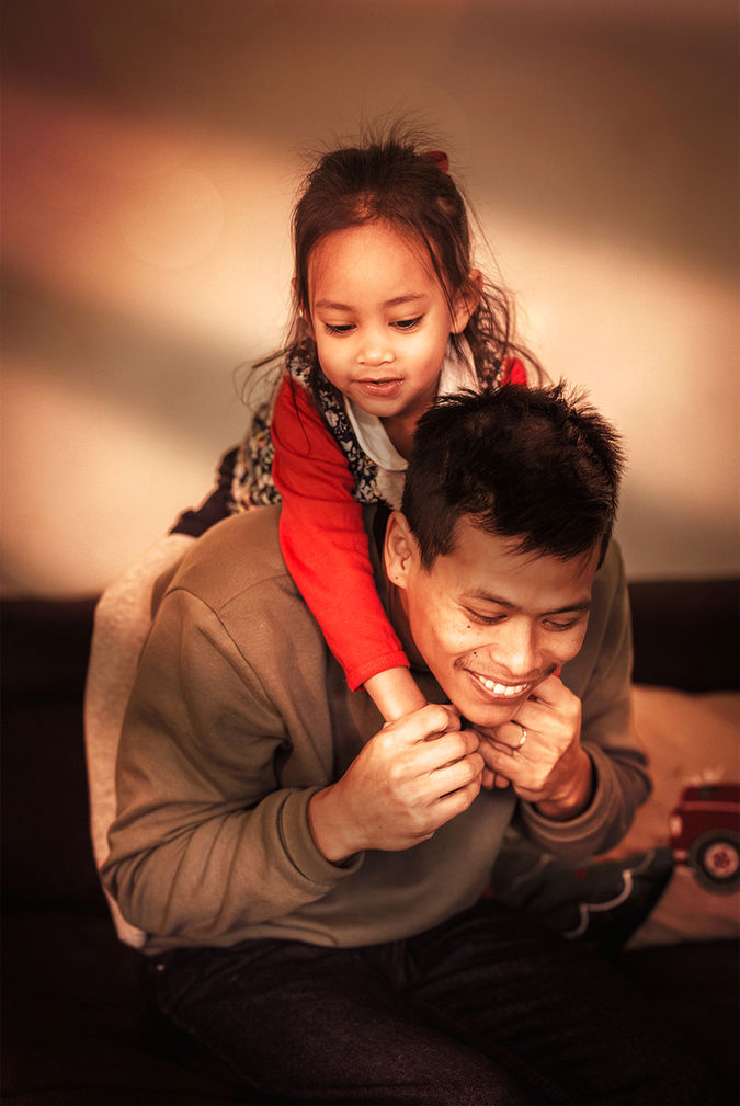 Homme souriant portant une petite fille joyeuse sur ses épaules.
