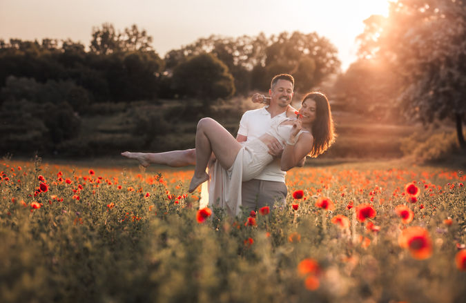 Couple dans un champ de coquelicots au coucher du soleil