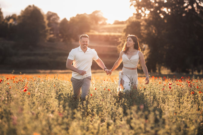 Couple joyeux courant dans un champ fleuri au coucher du soleil.