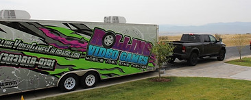 Rolling Video Games Colorado trailer and truck in a front lawn. There are mountains in the background.