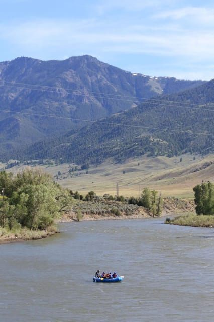 A rafting tour taking a comfortable scenic float down the Yellowstone River with mountains in the background.
