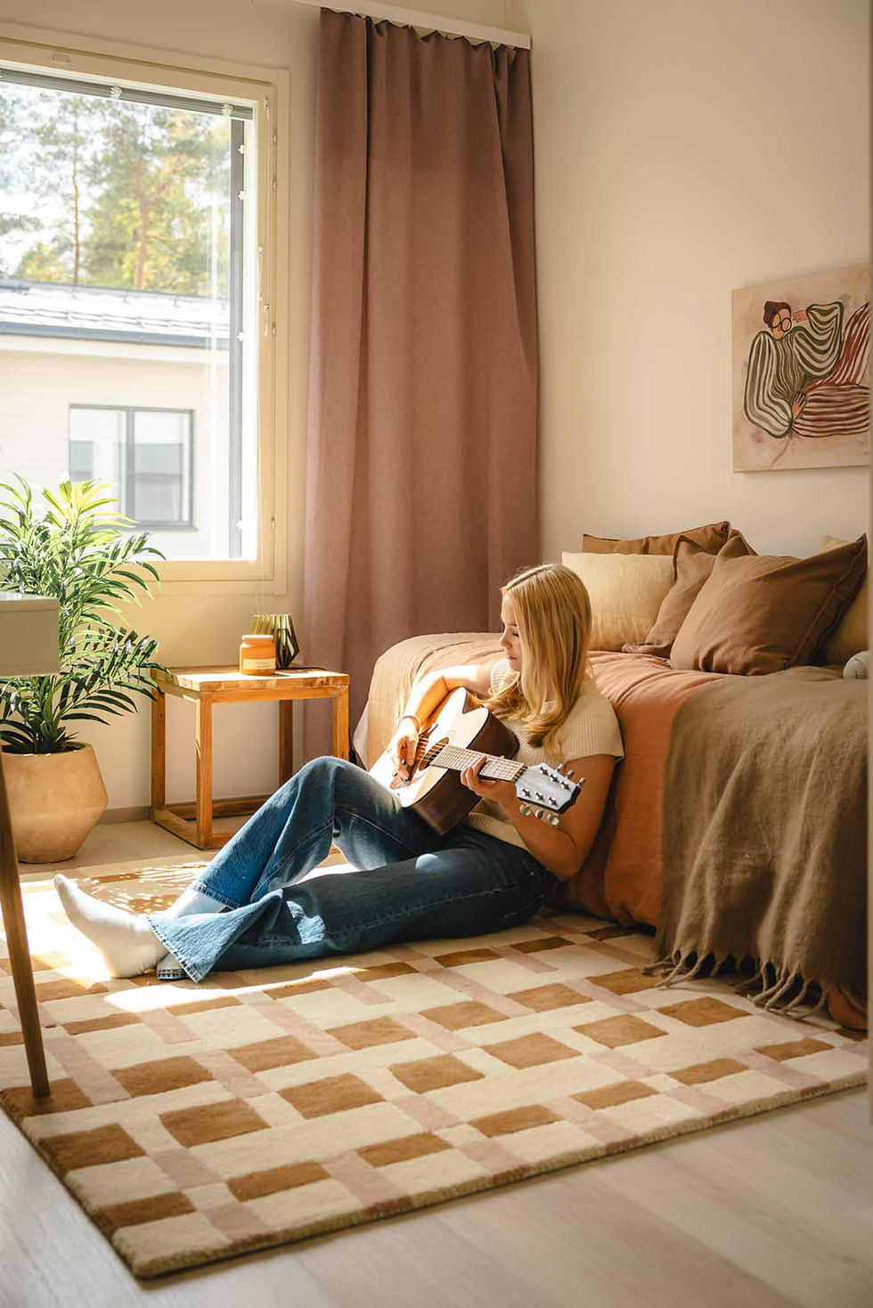 Tyttö soittaa kitaraa pinkissä huoneessa