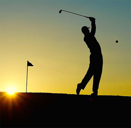 Golfer schlägt Ball bei Sonnenuntergang