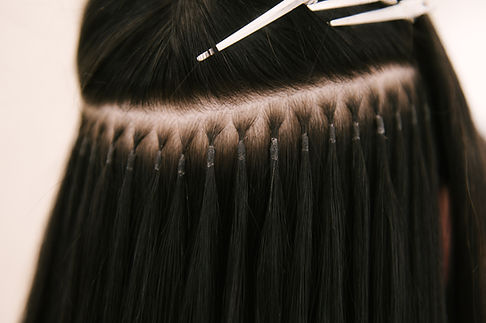 The hairdresser does hair extensions to a young girl in a beauty salon. Professional hair