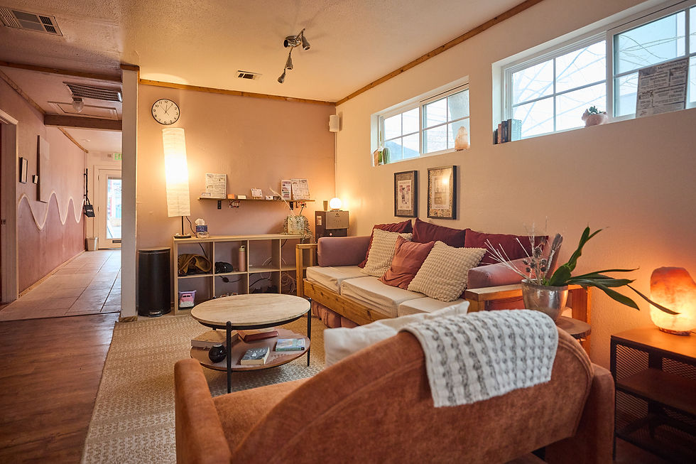 back lobby view of the austin salt room -- warm, moody, welcoming, couches with blankets and pillows, a himalayan salt lamp glow, cubbies, and a coffee table with books and games below -- visit austin salt room for a unique halotherapy experience!