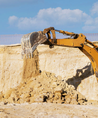 Excavator digging sand at construction site