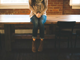 Person sitting alone at a wooden table with hands clasped, illustrating shutting down during hard conversations and emotional freeze response.