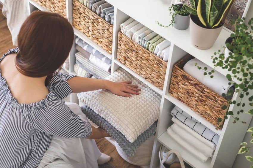 a woman sitting on a chair in front of a shelf filled with pillows