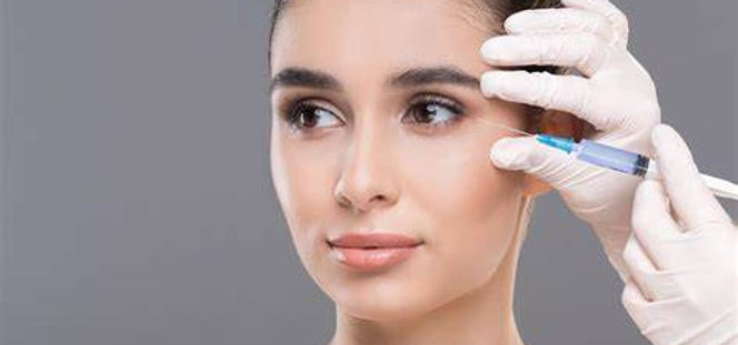 A close-up image of a needle positioned just below a woman's eye before administering tear trough filler, highlighting the treatment area to reduce dark circles and under-eye hollows.